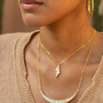 Rishi Bolt Diamond gold vermeil pendant necklace on woman wearing hoop earrings and beige top