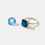 14k gold ring with cushion cut London Blue Topaz gemstone and loose light blue topaz stone on white background