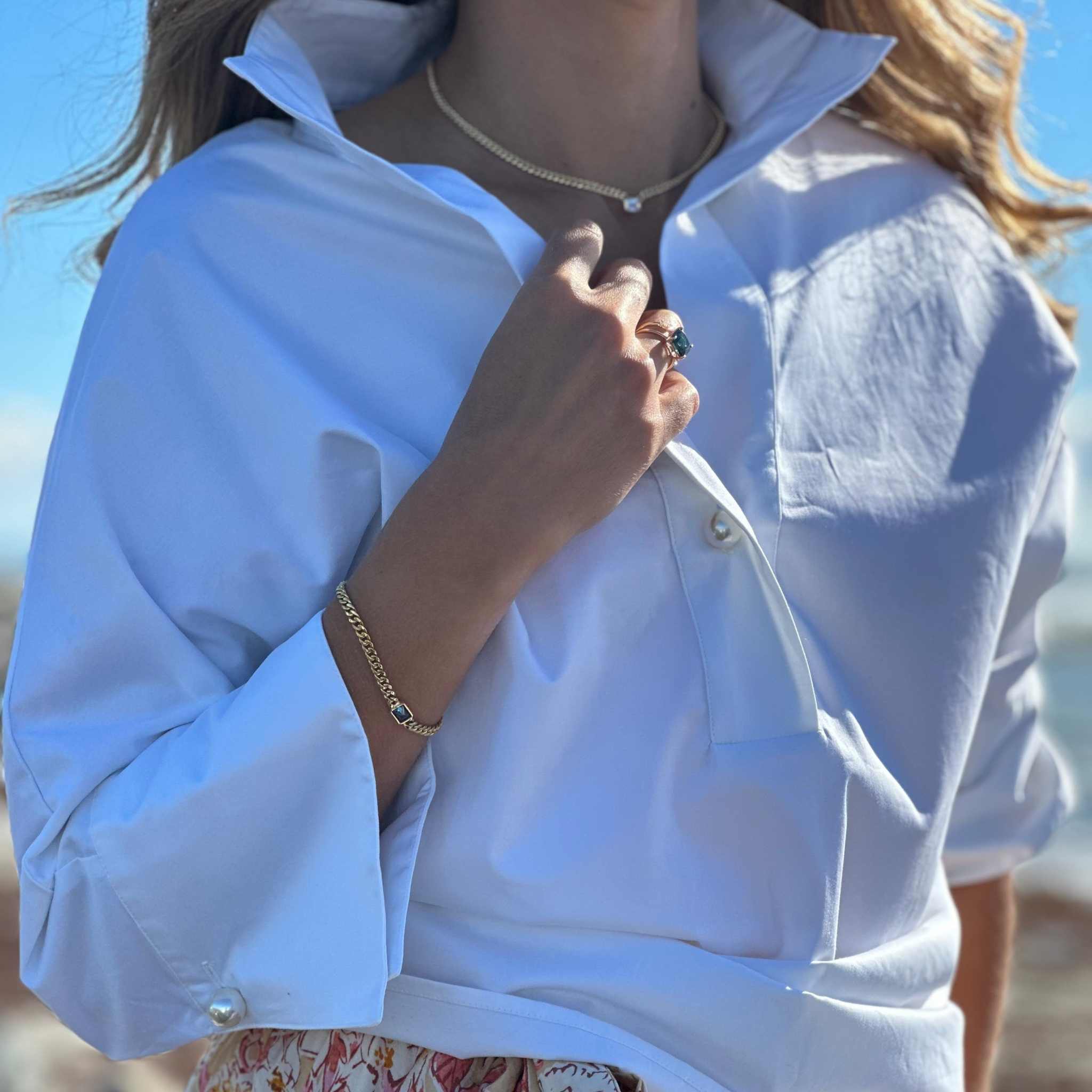 Woman wearing emerald cut diamond Cuban harbor necklace on Cuban chain with white shirt and bracelet outdoors