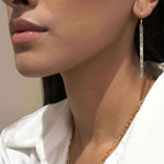 Close-up of a woman wearing Miladi Large Gold Vermeil Earrings with long dangling geometric design and sliced raw uncut diamonds.