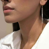 Close-up of a woman wearing Miladi Large Gold Vermeil Earrings with long dangling geometric design and sliced raw uncut diamonds.