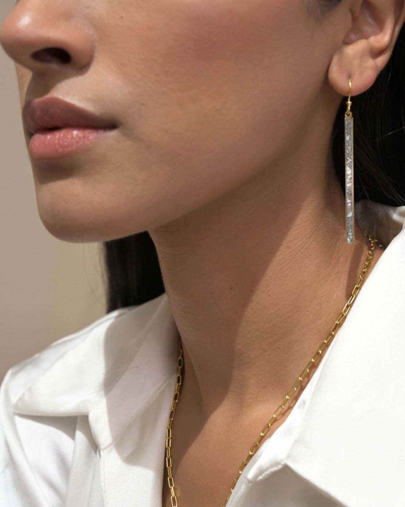 Close-up of a woman wearing Miladi Large Gold Vermeil Earrings with long dangling geometric design and sliced raw uncut diamonds.