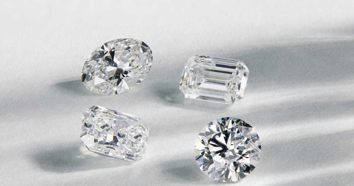 Four sparkling cut diamonds in various shapes displayed on a light surface representing the April birthstone diamond.