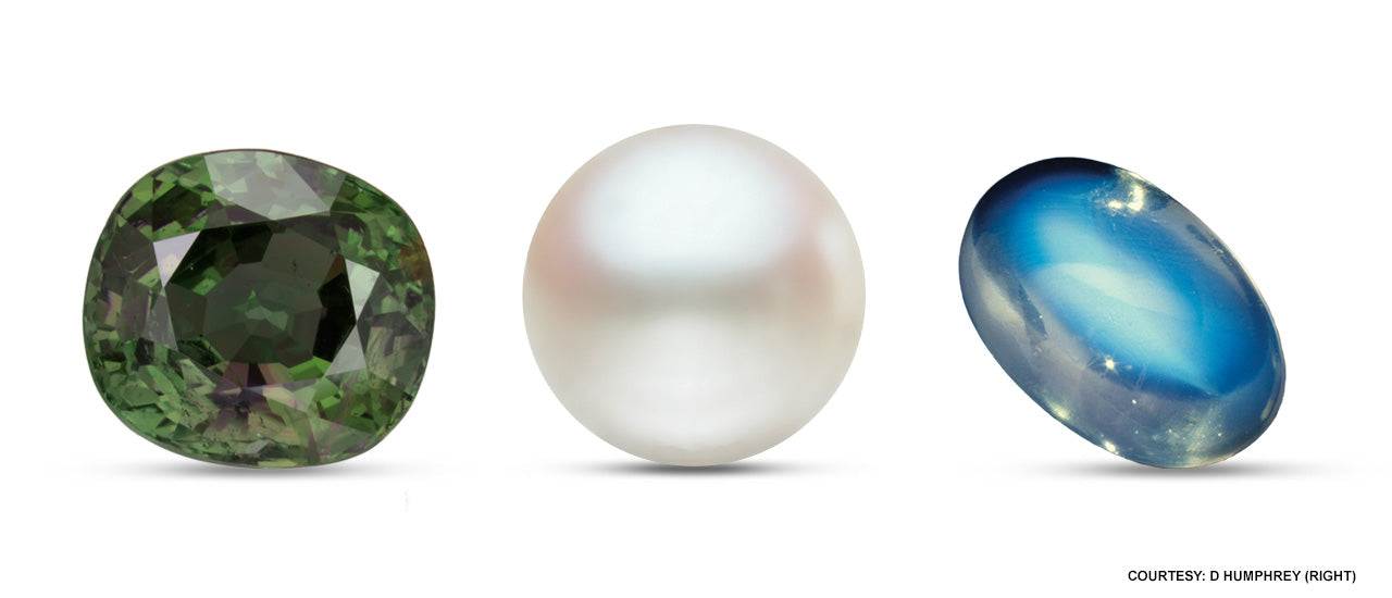 Three June birthstones including a greenish alexandrite, a white pearl, and a blue moonstone on a white background.
