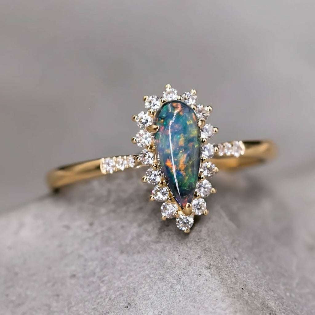 18K yellow gold engagement ring with pear-shaped Australian black opal surrounded by halo diamonds
