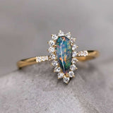 18K yellow gold engagement ring with pear-shaped Australian black opal surrounded by halo diamonds