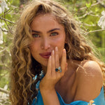 Woman with curly hair wearing a sky light blue topaz ring on finger in natural outdoor setting