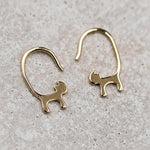 18K yellow gold cat tail hook earrings in a minimalist design on a textured surface