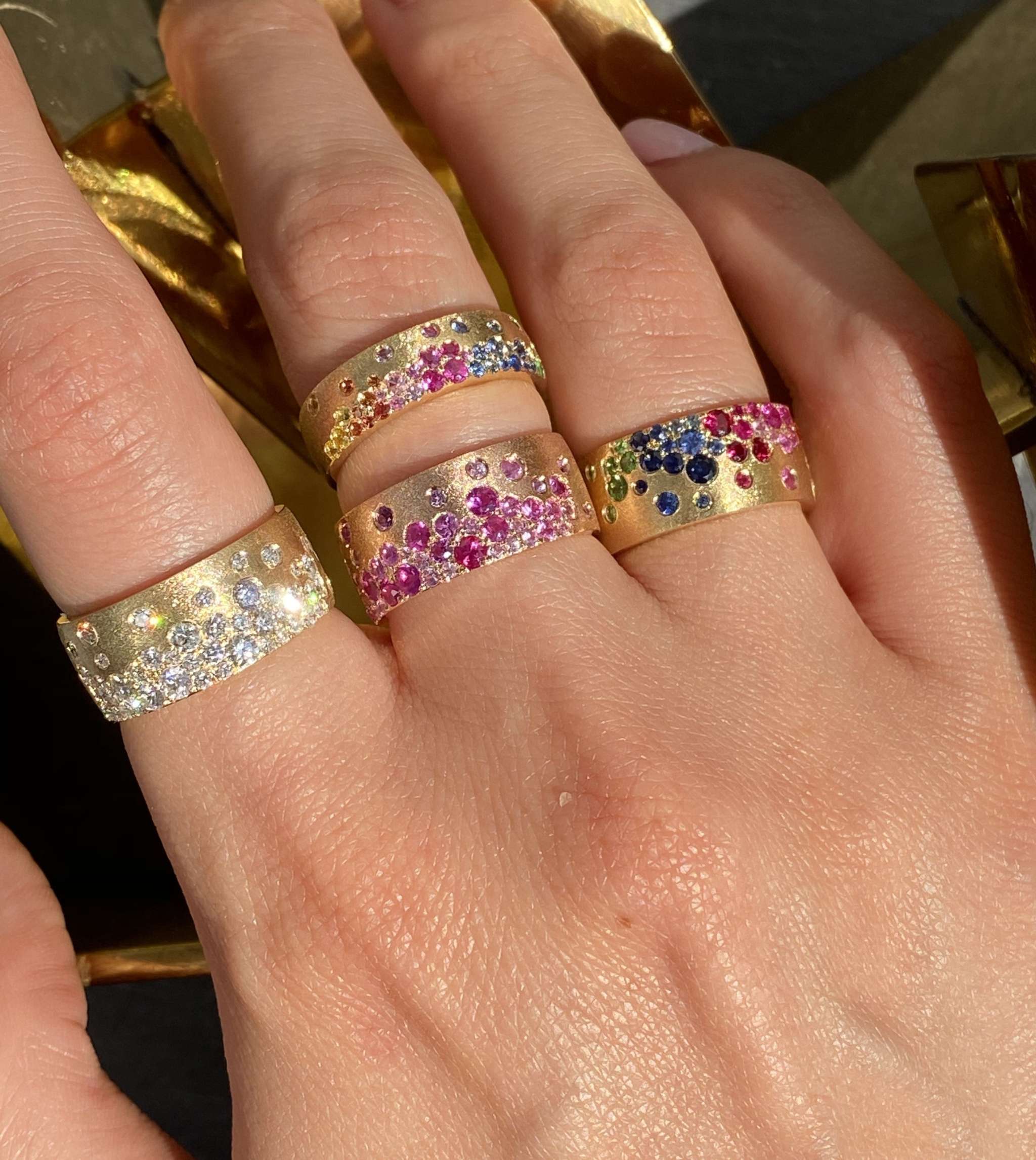 14K gold Sapphire Scattered Rainbow mini cigar band ring with rainbow sapphires on hand