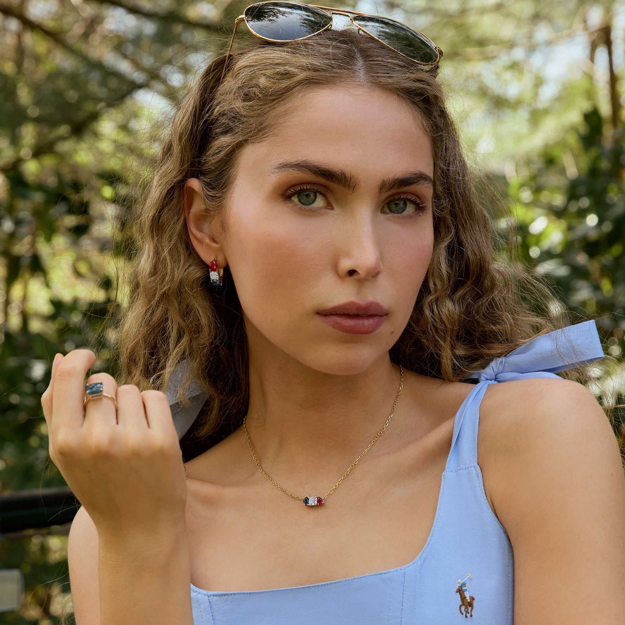 Woman wearing Americana Signature Three-Stone Ring with cushion-cut diamond, ruby, and sapphire in 14k gold