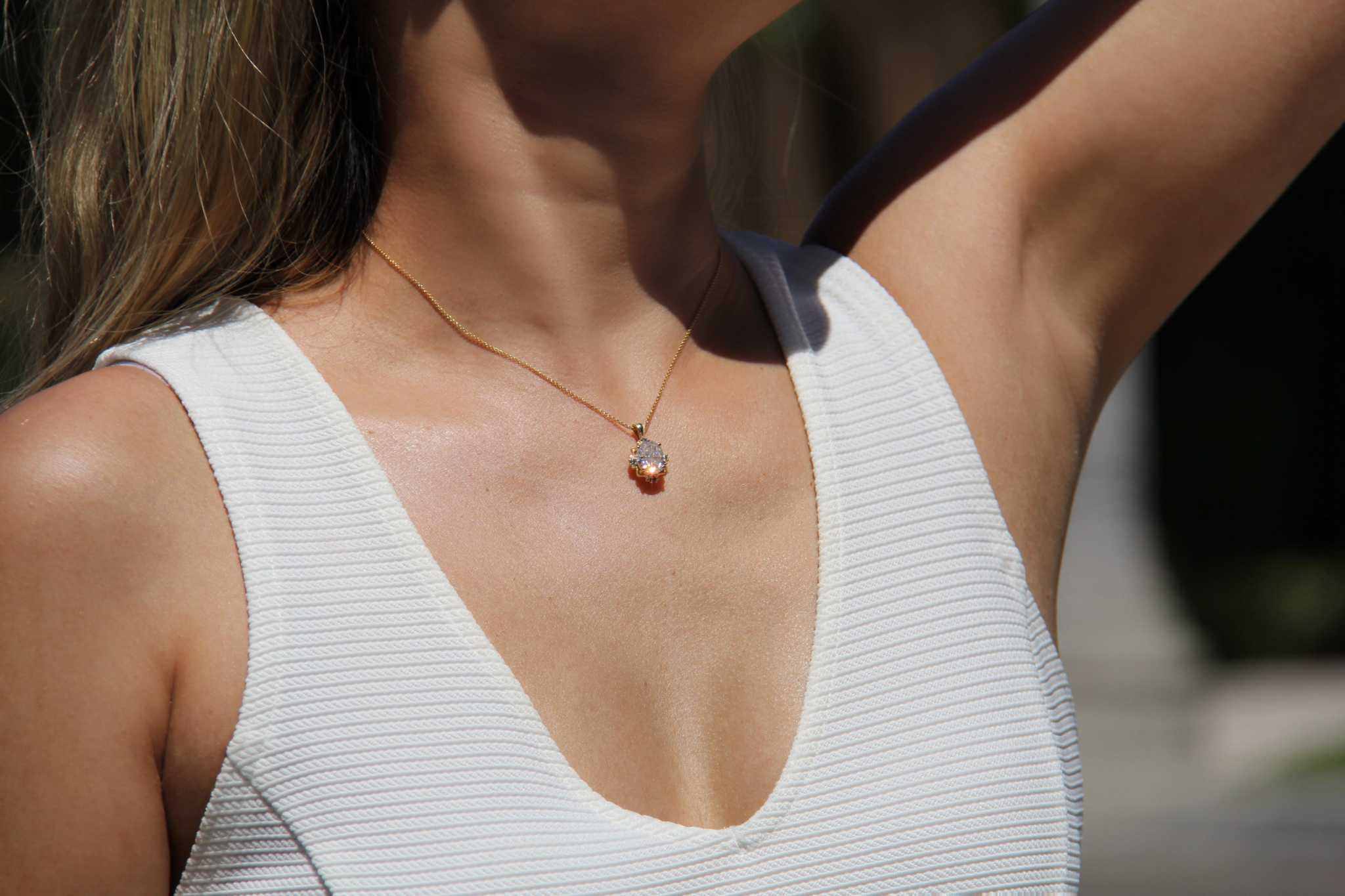 14K yellow gold pendant with 4.2 CT oval moissanite and 4 natural alexandrite stones in vintage-inspired mirror style worn by woman in white top