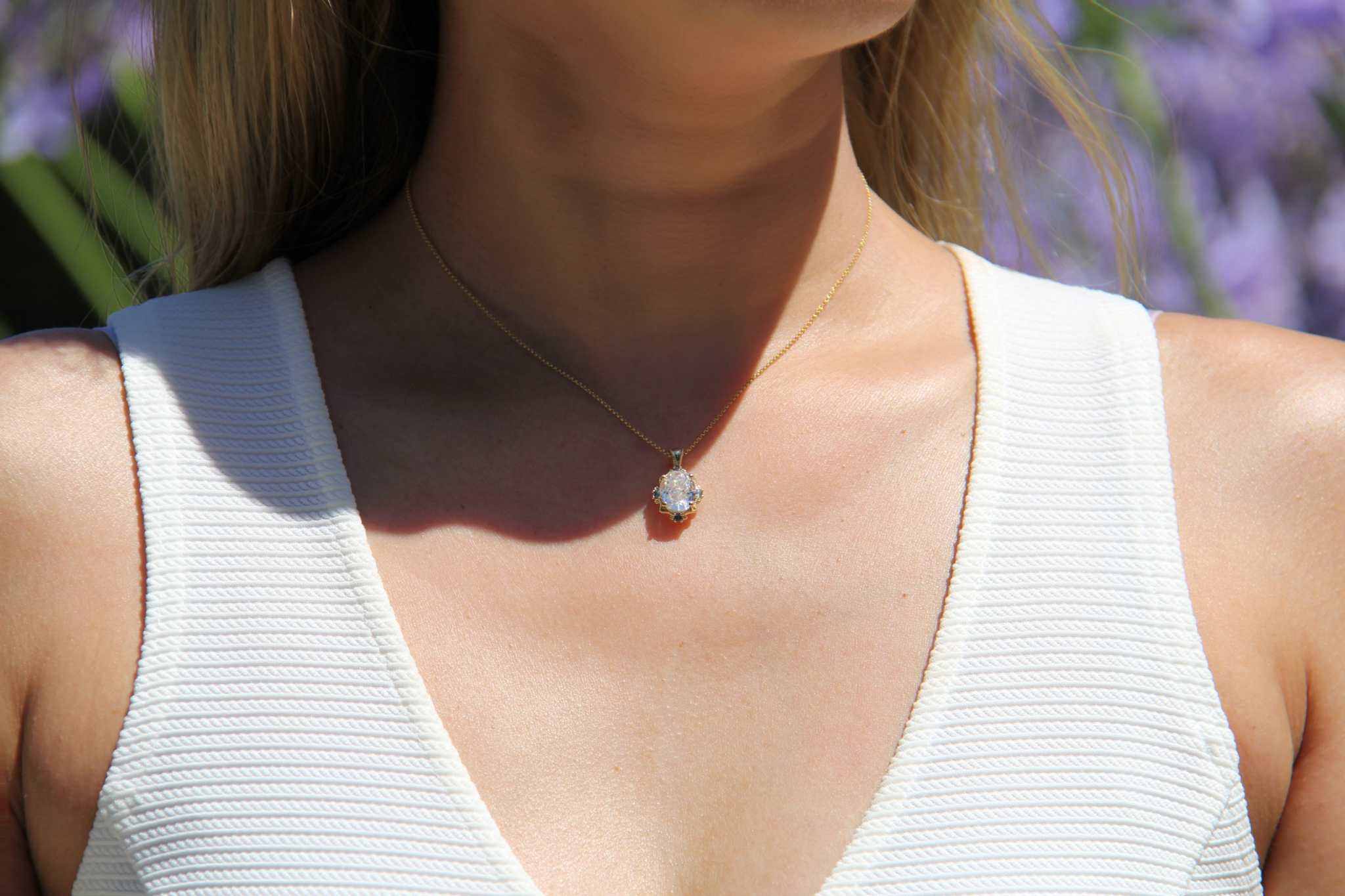 14K yellow gold oval moissanite pendant with 4 natural alexandrite stones worn on a woman in a white sleeveless top, vintage inspired mirror style necklace