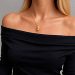 24K gold Labubu doll pendant necklace worn on woman in off-shoulder black top