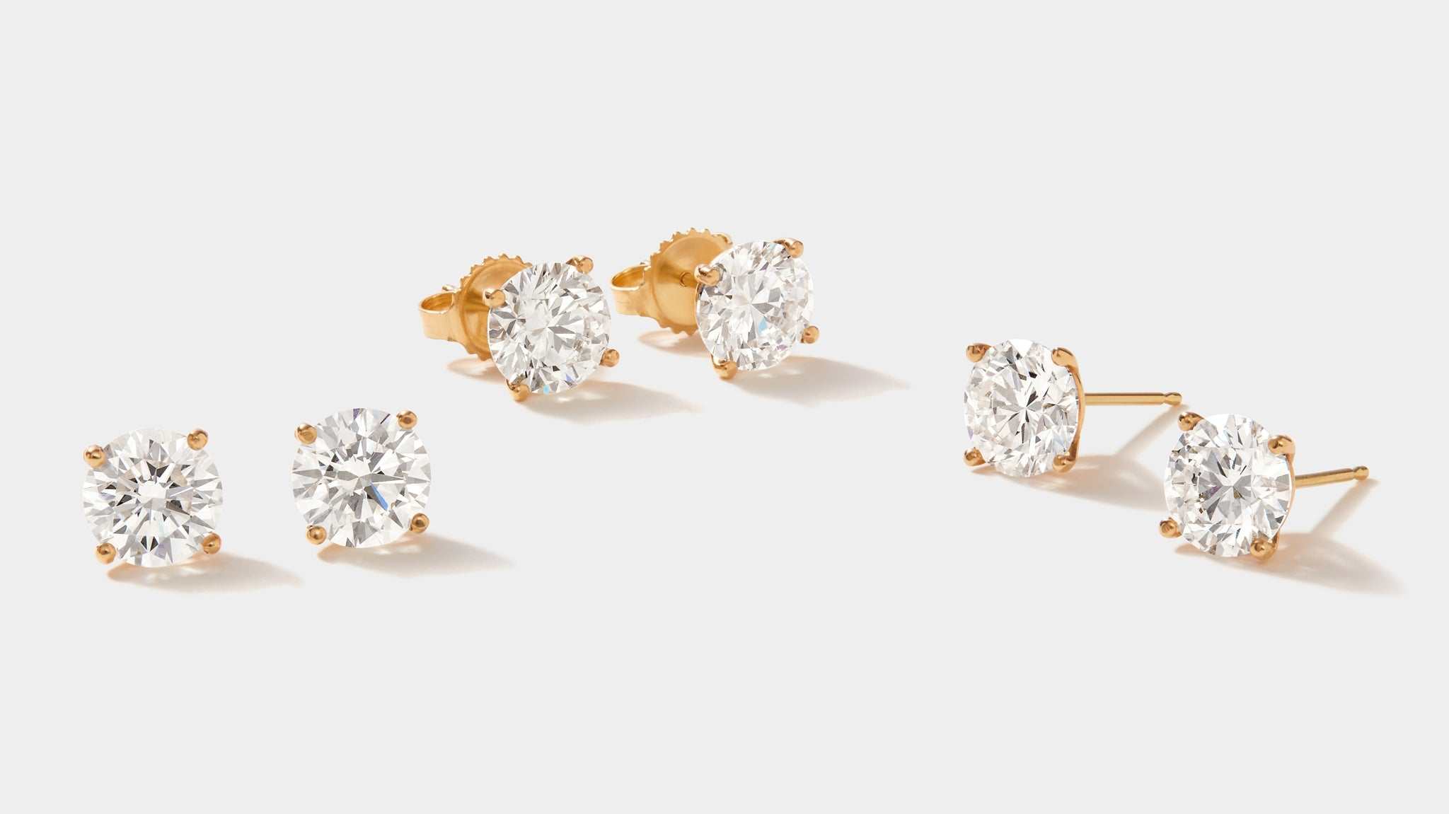 Set of lab grown diamond stud earrings in 14k gold four-prong martini setting with round FG VS2 diamonds totaling 3 carats.