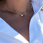 Emerald cut diamond bezel-set on 10k yellow gold Cuban chain necklace worn with white shirt