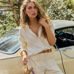 Woman wearing Horizon Sapphire New York 8mm lab-grown sapphire pendant in 14k gold on layered chains with beige outfit near vintage car outdoors