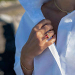 Boston Red Ring featuring 14k gold and cushion cut lab-grown ruby worn on finger with white blouse background