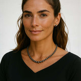 Elegant black freshwater pearl strand necklace worn by woman with black top and simple earrings