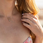 Woman wearing Harwich Thick Gold Rope Ring on finger with gold necklace and floral dress background outdoors sunlight