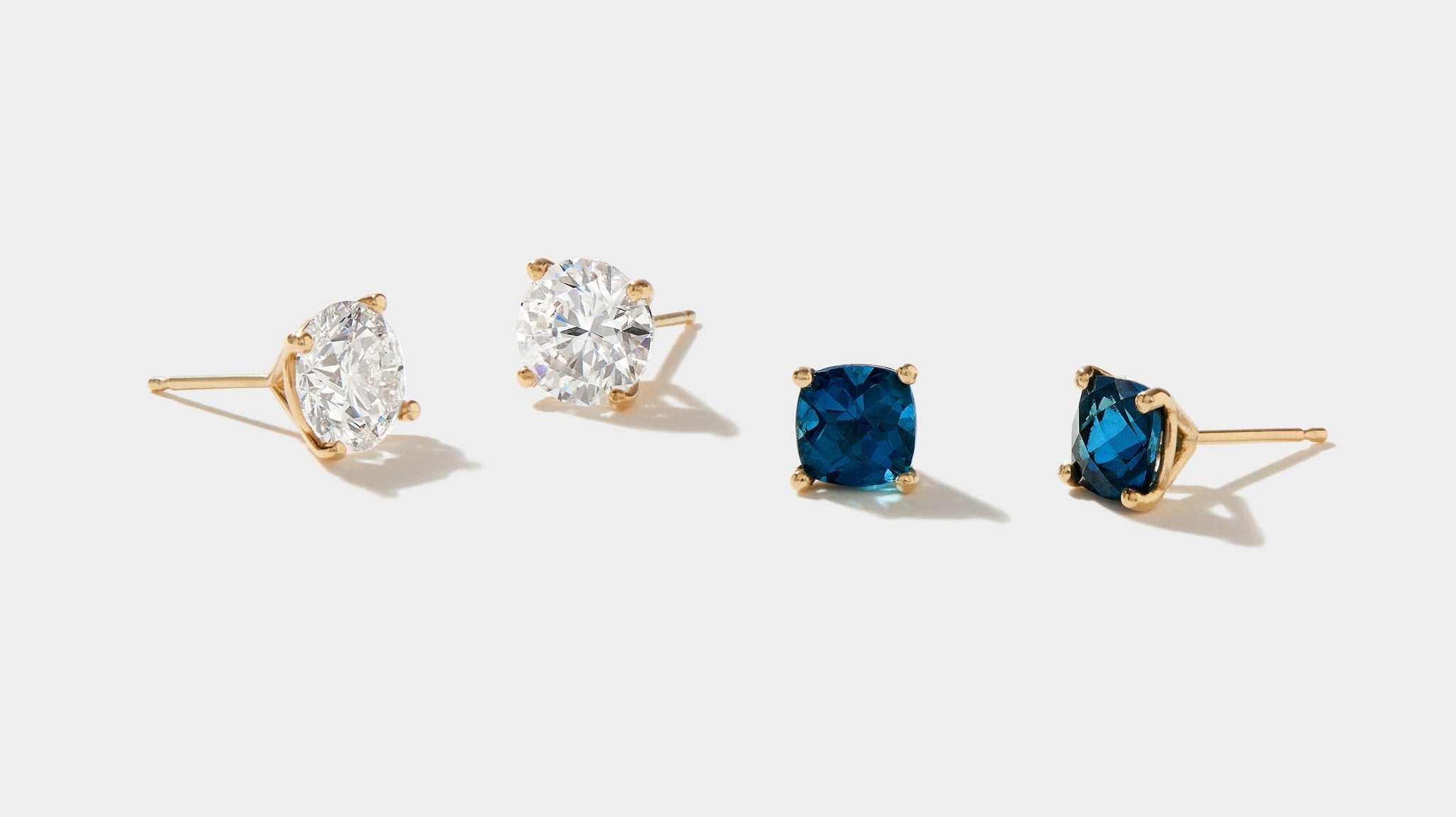 Tide Earrings featuring cushion cut London blue topaz and white gemstones set in 14k yellow gold stud mounts.