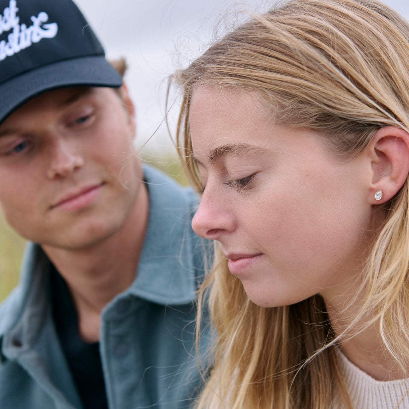 Woman wearing Great Point pear shaped diamond bezel earrings with man looking at her outdoors